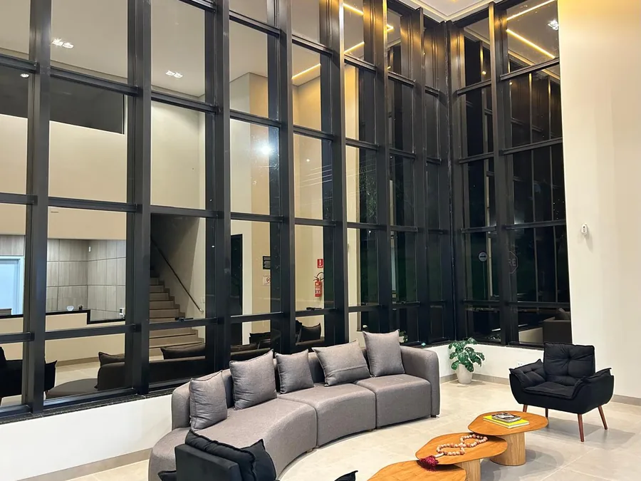 Sala de espera da clínica, com pé-direito duplo e parede de vidro