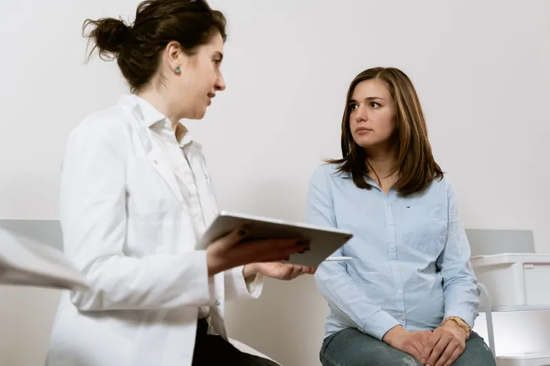 Médica conversando com uma paciente em consultório claro