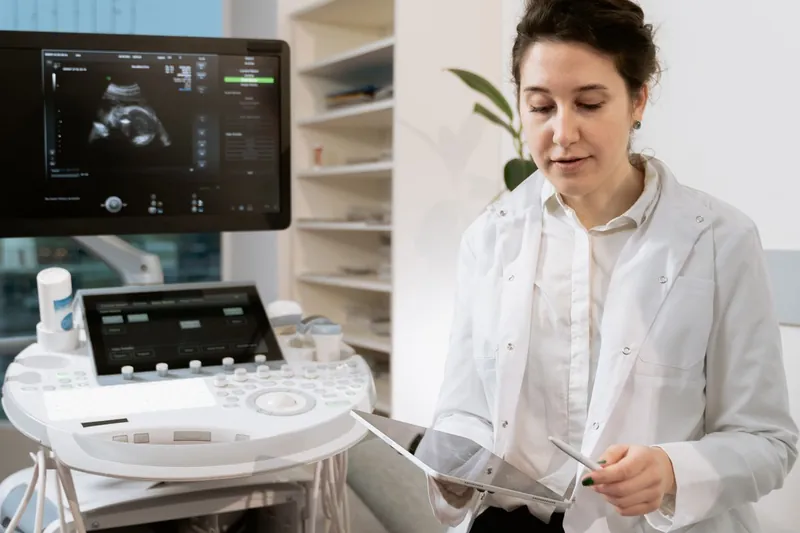 Médica ao lado do aparelho de ultrassom no consultório