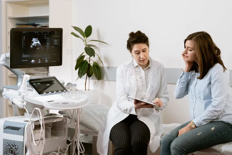 Médica orientando uma paciente na sala de exames