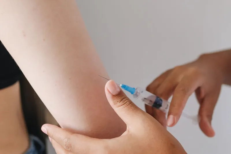 Aplicação de medicação injetável no braço de uma paciente